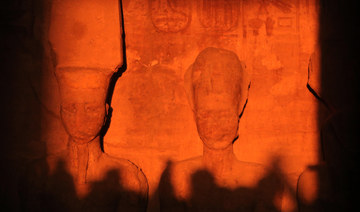 The sun illuminates the stone sculptures of (L to R) the deity Amun-Ra and King Ramses II.