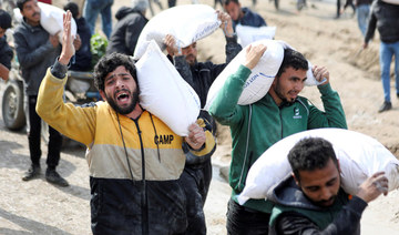Palestinians carry bags of flour they received from an aid truck near an Israeli checkpoint.